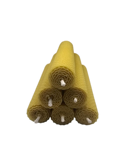 Ein kunstvoller, pyramidenförmiger Stapel aus mehreren handgerollten Stumpenkerzen aus reinen Bienenwachs-Wachsplatten, frontal fotografiert mit sichtbaren Dochten und Wabenstruktur vor weißem Hintergrund.